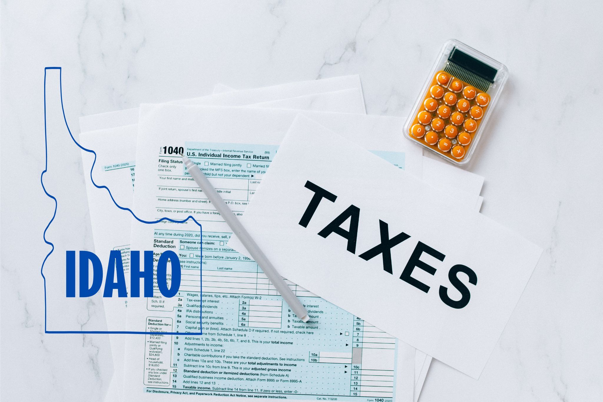 A capital gains calculator sits next to tax forms, a paper with the word 'TAXES', and an Idaho state logo on a white marble surface.